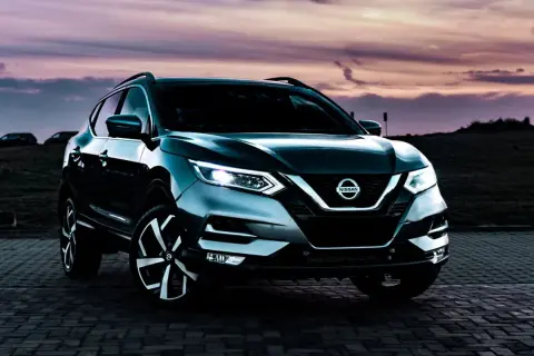 Mörkgrå Nissan Qashqai parkerad vid solnedgången. Kanske ett problem med bilen som gör att den står stilla?