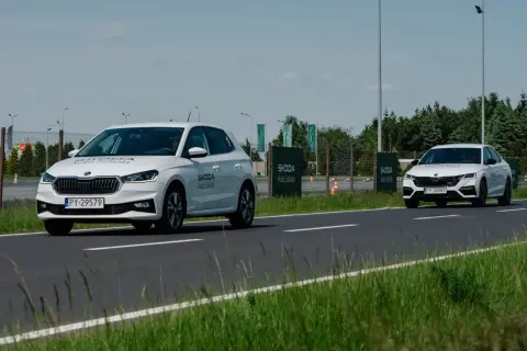 Białe Skody na torze szkoleniowym, jedna próbuje wyprzedzanie drugiej.