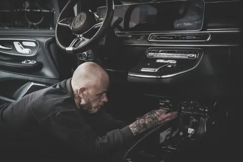 Ein Mechaniker mit Tattoos repariert den Anlasser eines modernen Autos.
