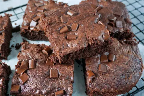 Saftige Zucchini-Brownies mit Schokoladenstückchen, die auf einem Gitterrost liegen.