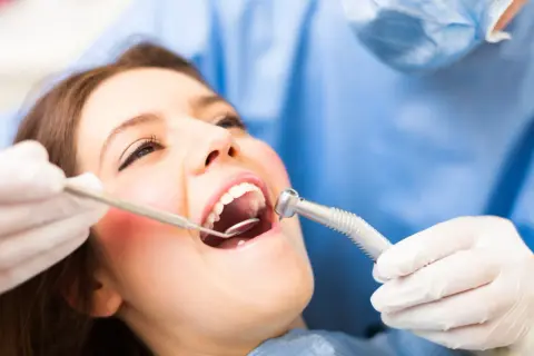 Pacjentka u dentysty, który bada jej dziąsło. Może to być związane z ropniem na dziąśle domowe sposoby.