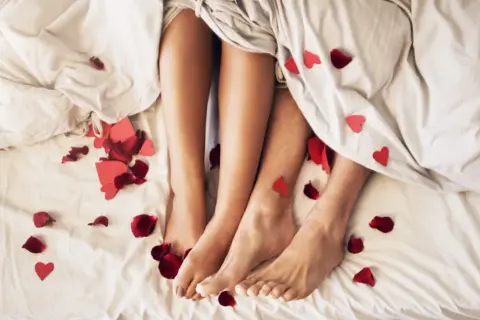Nogi pary pod kołdrą, wśród płatków róż i serduszek. Czy to początek romansu, czy może sex z przypadku?