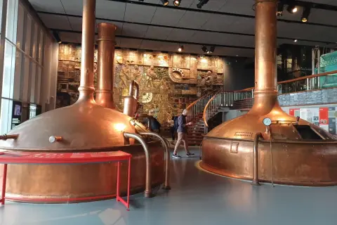 Interior del museo Estrella Galicia con grandes cubas de cobre y un mural histórico.