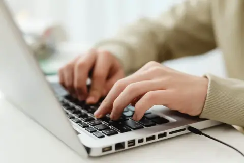 Mains sur un clavier d'ordinateur portable, utilisant des seo tools pour optimiser un site web.