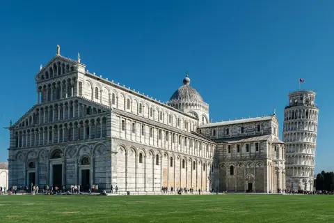 La piazza dei Miracoli a Pisa con il Duomo e la celebre torre di Pisa, simbolo della città, sotto un cielo azzurro.