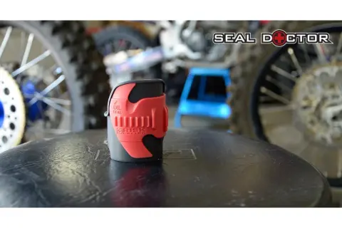 Herramienta roja para reparar horquilla moto, con logo "Seal Doctor" al fondo.
