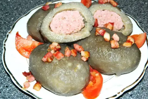 Cepelin z mięsem, polany skwarkami i podany z pomidorem. Pyszne danie kuchni litewskiej.
