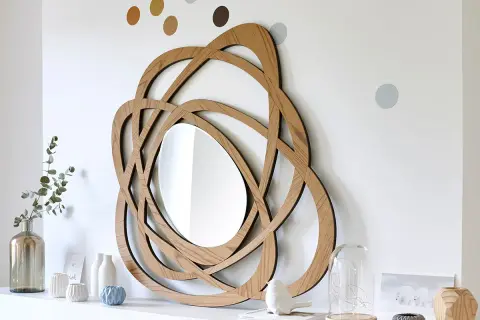 Miroir en bois au design entrelacé, parfait pour une diy deco murale. Des points colorés décorent le mur blanc.
