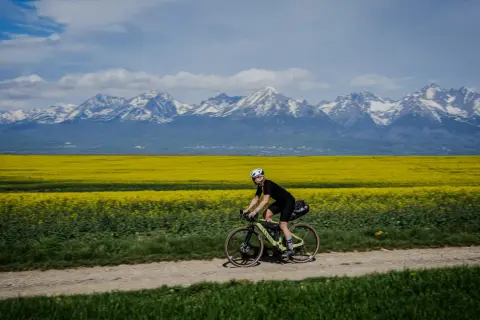 Rowerzystka pokonuje trasę rowerem dookoła Tatr w jeden dzień, mijając kwitnące pola rzepaku i ośnieżone szczyty.