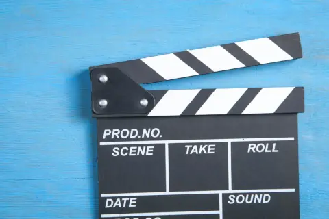 Klapka filmowa na niebieskim tle. Zastanawiasz się, ile zarabiają polscy aktorzy za jeden dzień zdjęciowy w hicie kinowym?