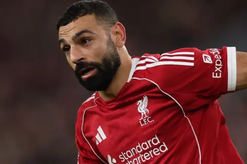 Piłkarz Liverpoolu w czerwonej koszulce, z zarostem i charakterystycznym spojrzeniem. To właśnie tam gra Salah, zdobywając kolejne bramki.