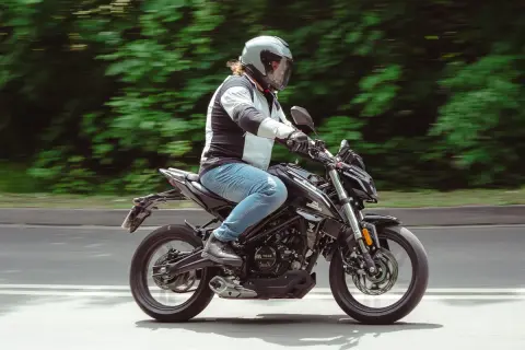 Motocyklista w kasku pędzi na czarnym Romet 125, pokonując kolejne 15 km.