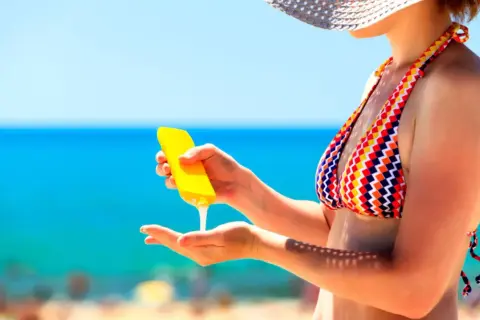 Frau trägt Sonnencreme auf, um sich vor der Sonne zu schützen. Wichtig: Sonnencreme mehrmals auftragen!