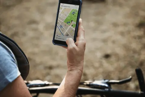 Rowerzysta sprawdza na telefonie mapę z trasą. Lokalizator GPS do roweru pomaga znaleźć drogę.