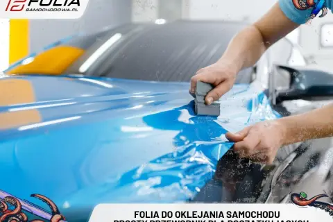 Ręce nakładają niebieską folię na maskę samochodu. Oklejanie auta to sztuka, którą każdy może opanować.