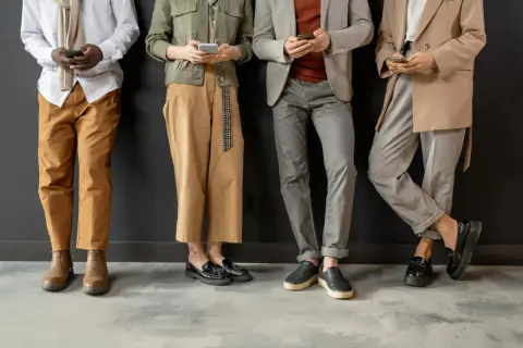 Cztery osoby w eleganckich strojach, trzymające telefony. Wszyscy przestrzegają dress code elegant.