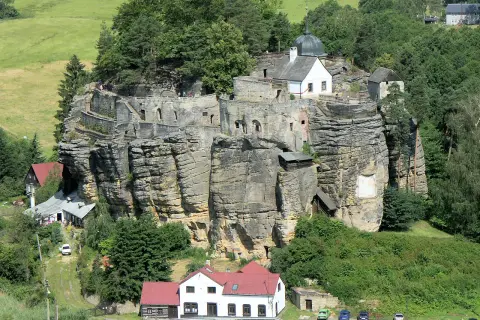 Felsenburg Einsiedlerstein thront auf einem Sandsteinfelsen, umgeben von grünen Hügeln und Wäldern.
