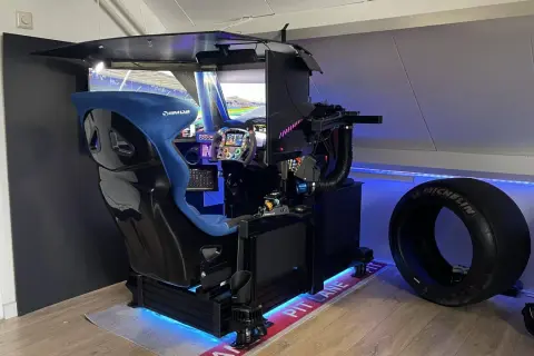 Ein beeindruckender **sim rig selber bauen**-Aufbau mit Rennsitz, Lenkrad und mehreren Bildschirmen. Daneben ein Rennreifen.