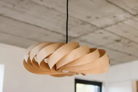 Lampada fai da te in legno, con lamelle curve che creano un effetto a spirale. Un pezzo unico che illumina con stile.