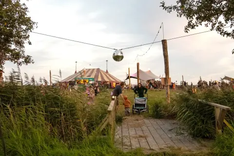 Ein buntes Zirkuszelt und Menschenmassen beim Calluna Festival. Eine Discokugel funkelt über dem Gelände.