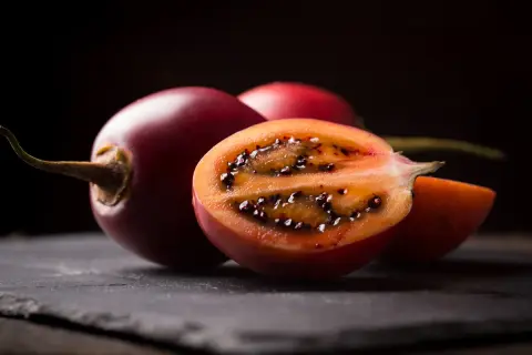 Tamarillo jak jeść? Pokrojone na pół, z widocznym miąższem i czarnymi nasionami, zachęca do spróbowania.