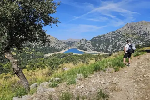 Randonneur contemplant le lac du Gorg Blau, un paysage emblématique du GR221 à Majorque.