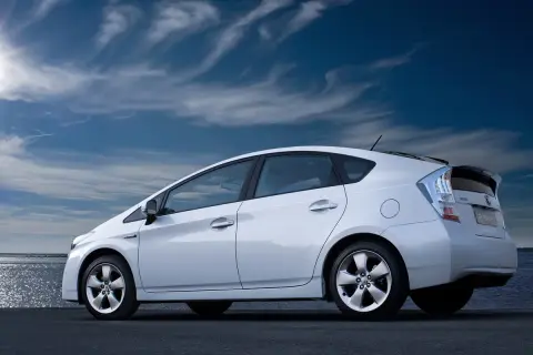 Biały Toyota Prius 3 na tle błękitnego nieba z chmurami.