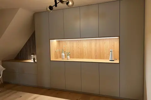 Moderne Einbauschränke gestalten eine gemütliche Schlafnische mit beleuchtetem Holzelement und Deko.