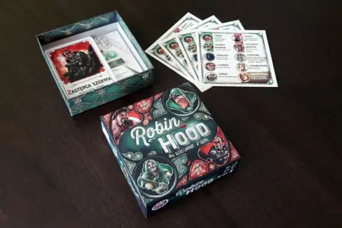 Planszowa gra robin hood gra, gdzie gracze wcielają się w postacie z Sherwood. Zestaw zawiera pudełko, karty postaci i inne elementy.
