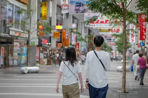 Para dowiedzieć się, jak rozmawiać z chłopakiem, obserwuj tę parę spacerującą po tętniącej życiem ulicy handlowej w Japonii, otoczonej neonami i sklepami.