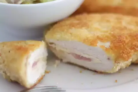 Un délicieux cordon bleu, pané et doré, révèle son cœur fondant de jambon et de fromage. Servi avec une salade verte.