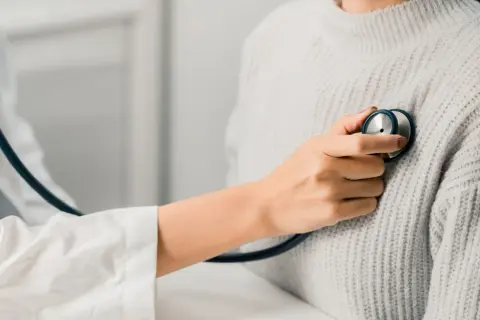 Un médecin écoute le cœur d'une patiente, cherchant un petit souffle au cœur.
