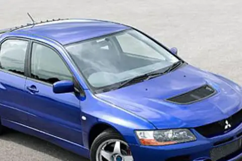 Niebieski Mitsubishi Lancer Evo 9 z charakterystycznym wlotem powietrza na masce i dużym spojlerem, gotowy do akcji.