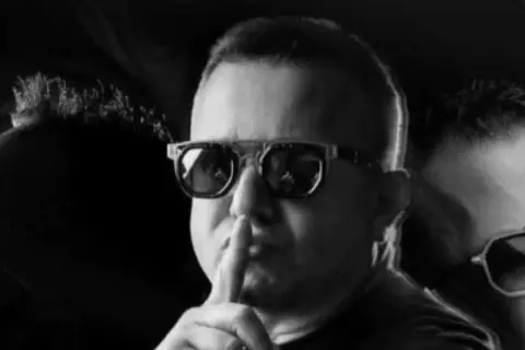 Dj Diesel w okularach z palcem na ustach, sugeruje ciszę przed nadchodzącym hitem.