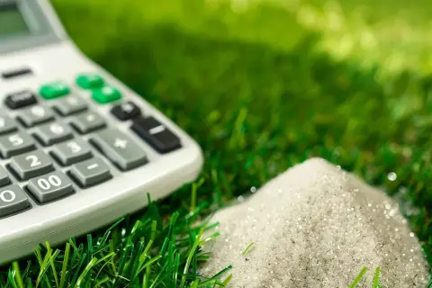 Calculadora sobre césped artificial, calculando la cantidad de arena para un proyecto de 100 m2.