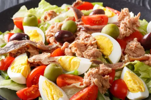 Ein appetitliches Salat Niçoise Rezept mit Thunfisch, Ei, Tomaten, Oliven und Sardellen auf knackigem Salat.