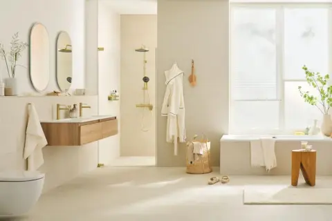 Helles, modernes Badezimmer mit cremefarbener Wandgestaltung. Goldene Armaturen und Duschkopf setzen Akzente. Die Farbgestaltung des kleinen Badezimmers ist beruhigend.