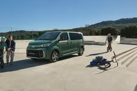 Grön Toyota Proace Verso parkerad vid en skatepark. En pappa och dotter med cyklar, en pojke på BMX.