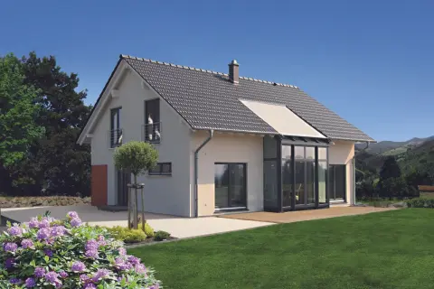 Modernes 1,5-geschossiges Haus mit Satteldach und Glasanbau. Der Grundriss bietet viel Licht und Raum.