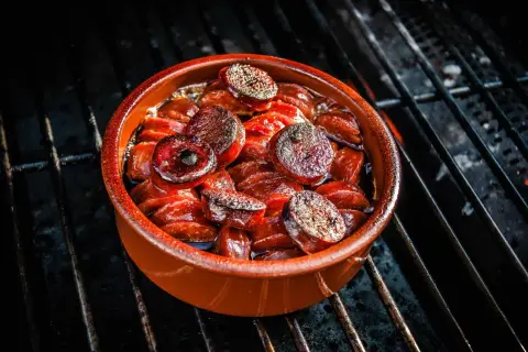 Heiß gegrillte Chorizo-Tapas in einer Tonschale, die auf einem Grillrost brutzeln.