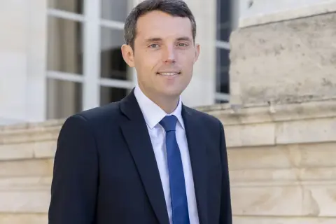Alexandre Portier, souriant, en costume sombre, prêt pour son mariage.