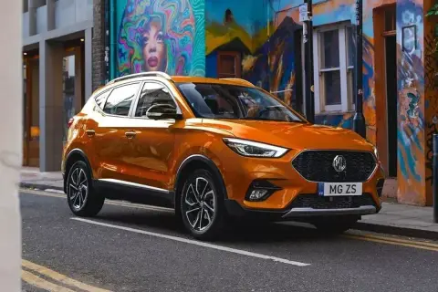 Pomarańczowe auto MG ZS na tle kolorowego muralu.