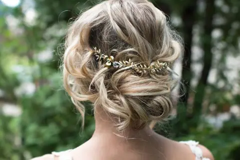 Recogido con trenzas boda, adornado con una delicada diadema dorada con detalles de pedrería.