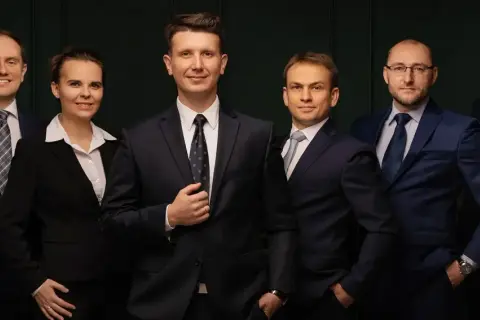 Grupa sześciu profesjonalistów w garniturach, stojących obok siebie.