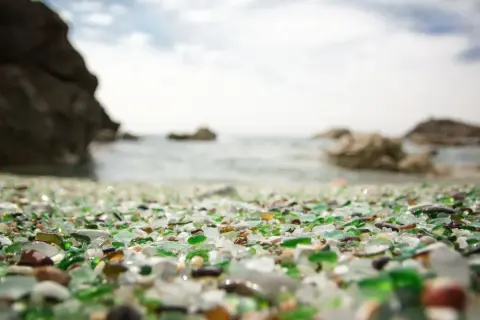 La playa de los cristales, un tesoro de vidrio pulido por el mar, se extiende ante rocas y el océano.