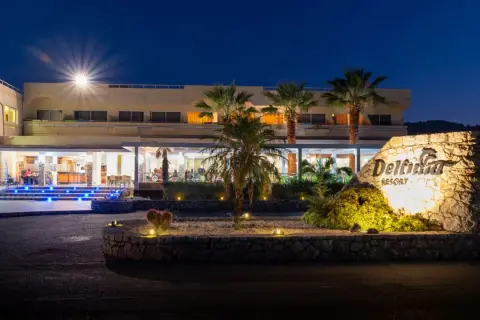 Nocny widok na Delfinia Resort. Podświetlone schody prowadzą do wejścia. Kamienny znak z nazwą hotelu.