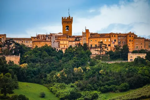 Un borgo storico su una collina verdeggiante, con una torre campanaria che domina la **città di Leopardi**.