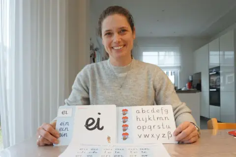 Lehrerin zeigt Grundschulkindern den Buchstaben S und das Alphabet.