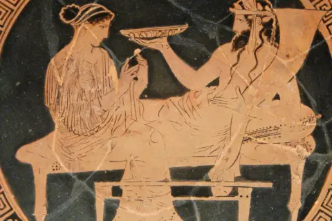 Scène antique : une femme, peut-être la femme d'Hadès, offre une coupe à un homme barbu.