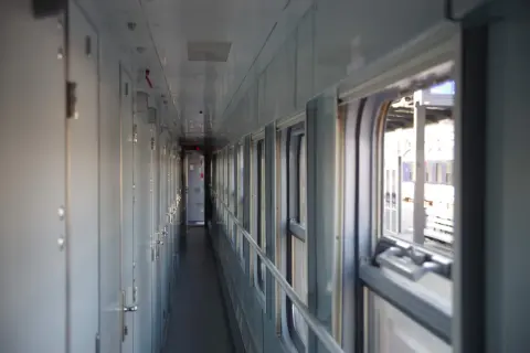 Korytarz wagonu sypialnego z rzędem drzwi po lewej i oknami po prawej.